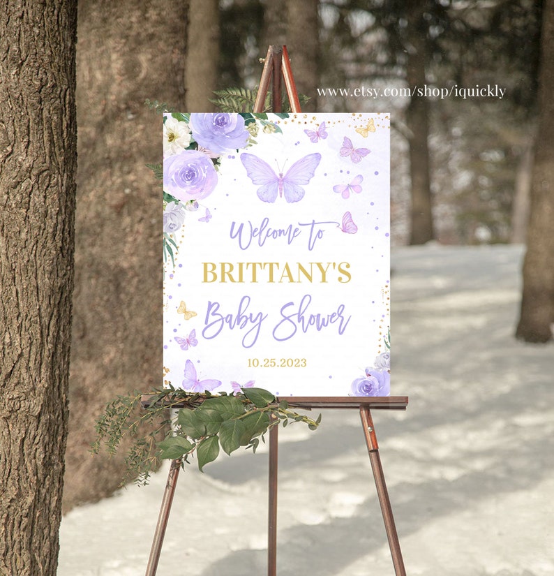 May include: Purple and gold baby shower welcome sign with butterflies and flowers. The sign says "Welcome to Brittany's Baby Shower 10.25.2023".