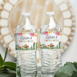 May include: Two clear plastic water bottles with colorful labels. The labels feature a cactus and sombrero design with the text "Lillian's Three-Esta".