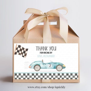 May include: A blue and white thank you favor box with a checkered flag and a blue race car with the number 2 on it. The text on the box reads "Thank you for racing by Love, Alexander".