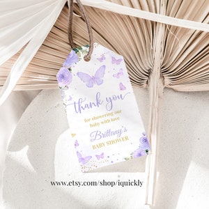May include: Purple and gold thank you tag with butterflies and flowers. The text reads "thank you for showering our baby with love Brittany's Baby Shower".