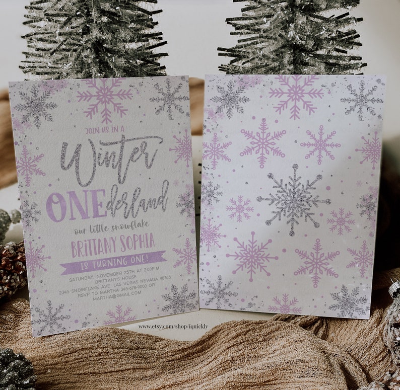 May include: A two-sided invitation with a winter theme. The front features the text "Winter ONEdrland" with snowflake accents in silver and lavender. The back has a pattern of snowflakes. The invitation is for Brittany Sophia's first birthday.