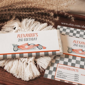 May include: A personalized chocolate bar wrapper with a checkered background and a red race car. The wrapper says "Alexander's 2nd Birthday".