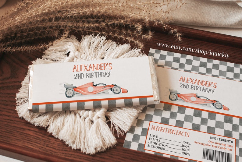 May include: A personalized chocolate bar wrapper with a checkered background and a red race car. The wrapper says "Alexander's 2nd Birthday".