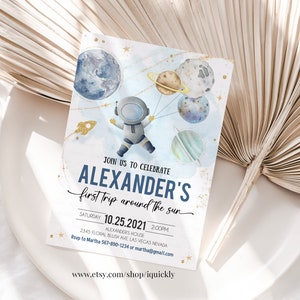 May include: A blue and white invitation with gold glitter accents. It features an astronaut holding balloons shaped like planets. The text reads "Join us to celebrate Alexander's first trip around the sun. Saturday 10.25.2021 2:00PM Alexander's House 2345 Floral Blush Ave Las Vegas Nevada Rsvp to Martha 567-890-1234 or martha@gmail.com www.etsy.com/shop/iquickly"