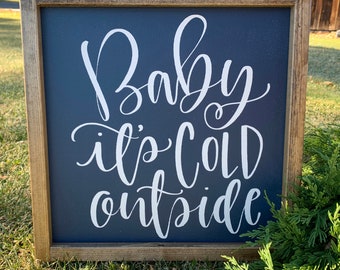 Può includere: Un cartello con cornice in legno, sfondo blu scuro e lettere bianche che recitano "Baby it's cold outside".