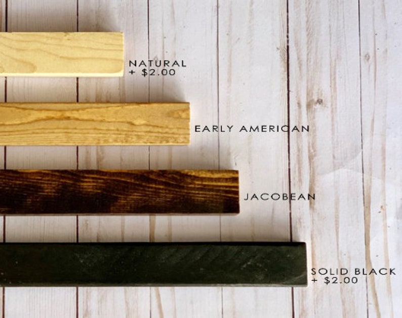 May include: Four wood samples in different colors: natural, early American, Jacobean, and solid black. The text "NATURAL + $2.00" is written below the first sample. The text "EARLY AMERICAN" is written below the second sample. The text "JACOBBEAN" is written below the third sample. The text "SOLID BLACK + $2.00" is written below the fourth sample.