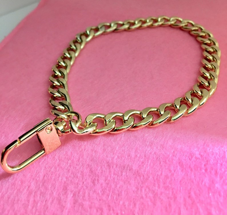 May include: A gold chain with a lobster clasp. The chain is thick and has a curb link design.