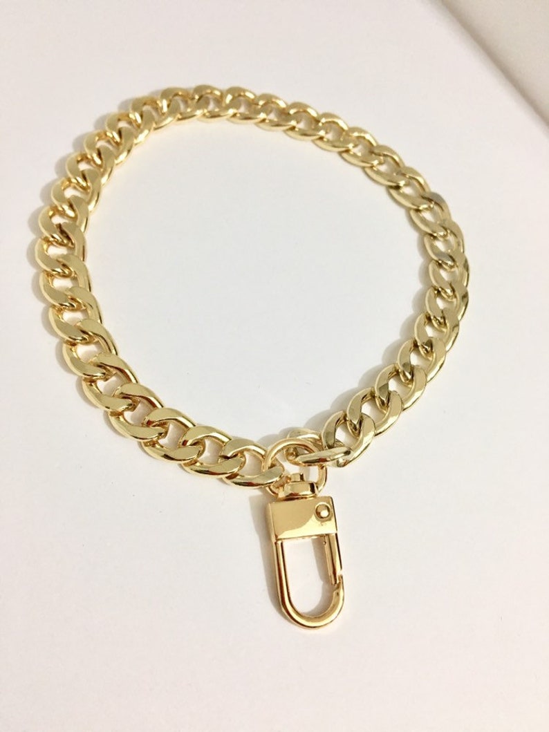 May include: A gold chain with a lobster clasp. The chain is thick and has a curb link design.