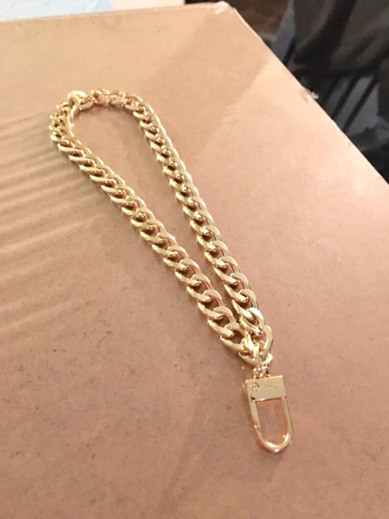 May include: A gold chain with a lobster clasp. The chain is made of thick, chunky links.