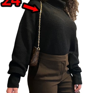 May include: A black mock neck sweater with long sleeves and a gold chain strap. The chain strap is 24 inches long. "Bag only for display" is written in black text on a white background at the bottom of the image.
