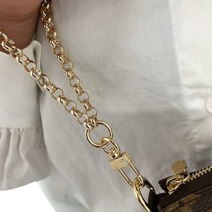 May include: A gold chain strap with a swivel clasp. The chain is double-layered and has a chunky, oval-link design.