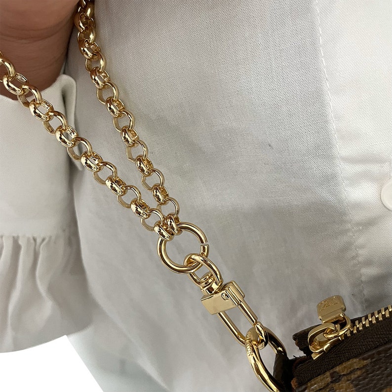 May include: A gold chain strap with a swivel clasp. The chain is double-layered and has a chunky, oval-link design.