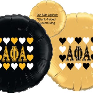 May include: Black and gold round foil balloons with the Greek letters AΦA and heart shapes. One balloon is black with gold and white hearts, and the other is gold with black and white hearts. Text on the gold balloon says "2nd Side Options: *Blank-1sided *Custom Msg".