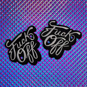 May include: Two black embroidered patches with the words "Fuck Off" in white cursive lettering. The patches are on a shiny, iridescent blue and purple background.