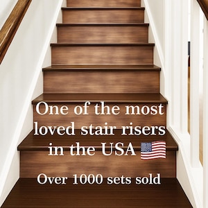 以下が含まれることがあります： 茶色の手すり付きの白い壁のついた木製の階段。階段には「One of the most loved stair risers in the USA  🇺🇸 Over 1000 sets sold」という文字が書かれています。