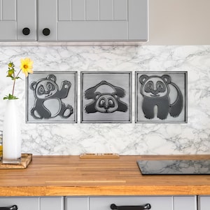 Op de afbeelding: Drie zwarte en witte pandabeer keramische tegels met een 3D-effect. De tegels zijn gemonteerd op een witte marmeren achterwand in een keuken.