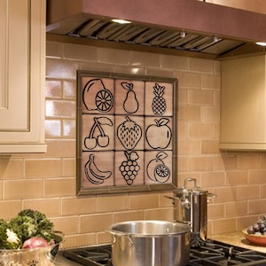May include: A kitchen with a copper range hood over a stainless steel stove with a black pot on the stovetop. The backsplash is tiled with a pattern of fruit silhouettes.