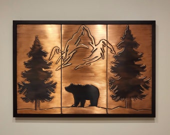 May include: A copper wall art piece depicting a bear standing in front of two pine trees and a mountain range. The artwork is framed in black.