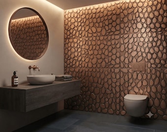 May include: A bathroom interior featuring a wall covered in copper-toned, pebble-shaped 3D tiles. The space includes a floating dark wood vanity, a white vessel sink, a round backlit mirror, a wall-mounted faucet, and a wall-hung toilet.