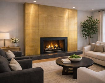 May include: A large fireplace featuring a metallic gold panel surround and a black frame. The firebox contains burning logs with visible flames. The fireplace is set into a wall above a dark stone hearth in a living room setting.