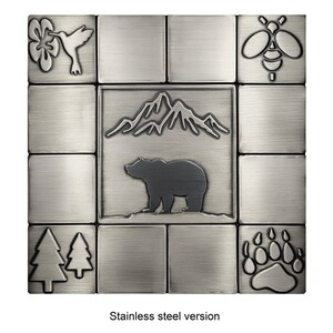 Puede incluir: Un conjunto de azulejos de acero inoxidable con un tema de naturaleza. Los azulejos presentan un oso, monta&ntilde;as, una abeja, un colibr&iacute;, una huella de pata y dos pinos.