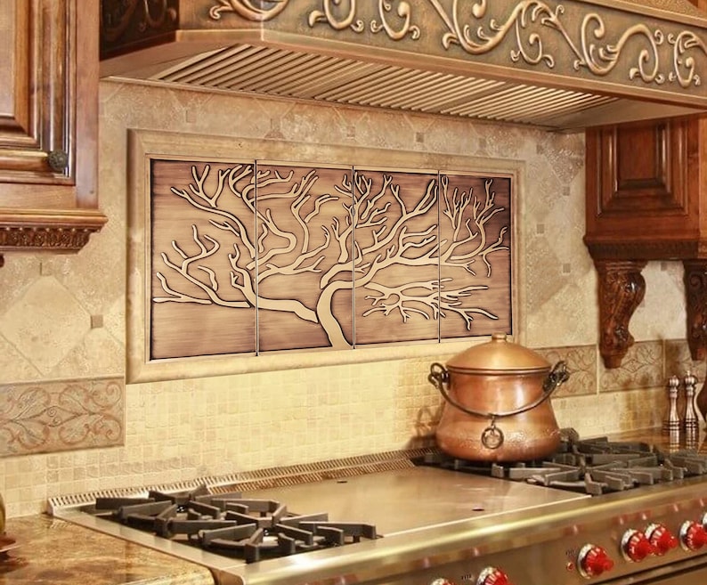 May include: A kitchen backsplash with a decorative tile design featuring a stylized tree in a copper finish. The backsplash is installed above a stainless steel stovetop with a copper pot on the counter.
