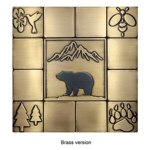 Puede incluir: Un juego de azulejos de lat&oacute;n con un tema de naturaleza. Los azulejos presentan un colibr&iacute;, una abeja, monta&ntilde;as, un oso, &aacute;rboles y una huella de pata de oso.