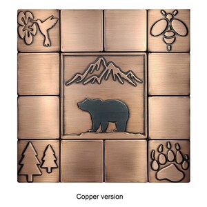 Puede incluir: Conjunto de azulejos de tono cobre con un oso, monta&ntilde;as, &aacute;rboles, un colibr&iacute;, una abeja y una huella de pata. Los azulejos est&aacute;n dispuestos en una cuadr&iacute;cula de 3x3.