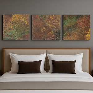 May include: A bedroom scene with a bed dressed in white and brown bedding, flanked by wooden bedside tables with lamps. Above the bed, three abstract art pieces in earthy tones hang on the wall.