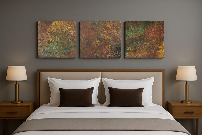 May include: A bedroom scene with a bed dressed in white and brown bedding, flanked by wooden bedside tables with lamps. Above the bed, three abstract art pieces in earthy tones hang on the wall.