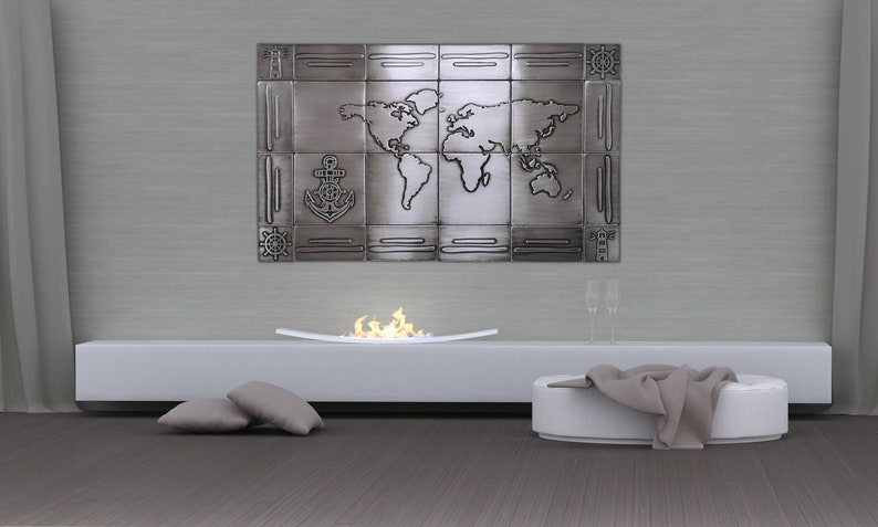 May include: A metal wall art piece featuring a world map design, an anchor, and nautical elements. The artwork is mounted above a white fireplace with a flame effect. The room includes a white bench, pillows, and a blanket.