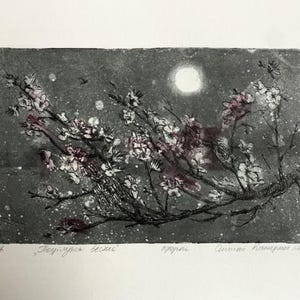May include: A rectangular etching print on paper featuring a dark, textured grey night sky with a bright circular moon. Flowering branches with white and soft pink blossoms stretch across the composition, accented by white speckles resembling stars.