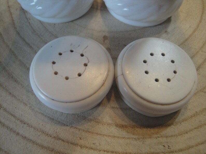 Pode incluir: Dois saleiros e pimenteiros de cer&acirc;mica branca com um design em espiral. Os saleiros t&ecirc;m uma parte superior redonda com furos para dispensar sal e pimenta.