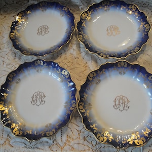 May include: Set of four blue and gold rimmed porcelain plates with a white center and a gold monogram in the center of each plate.