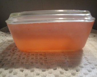 May include: A clear glass rectangular baking dish with a lid, filled with a pink gelatin dessert.
