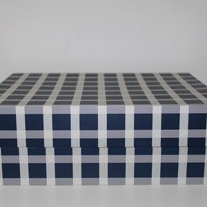 Könnte beinhalten: Eine blaue und weiße Schachtel mit Karomuster und einem Klappdeckel.