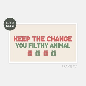May include: A beige background with a white frame around a red and green cross-stitched design that reads "KEEP THE CHANGE YOU FILTHY ANIMAL" with four red and green cross-stitched gift boxes below the text. The text "FRAME TV" is below the frame.