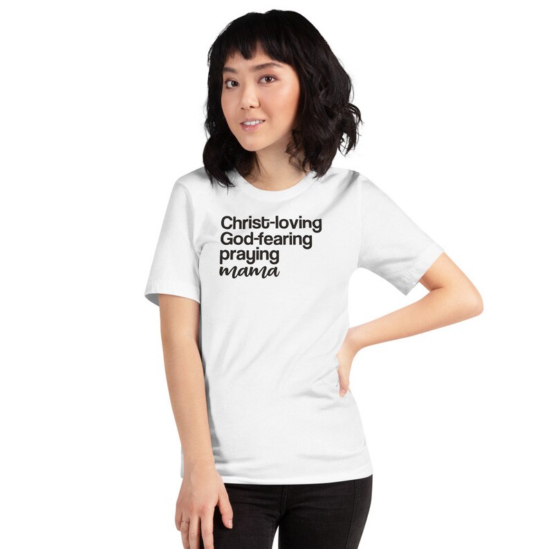 May include: White t-shirt with the text "Christ-loving God-fearing praying mama" in black. The shirt is a short-sleeved crew neck style.