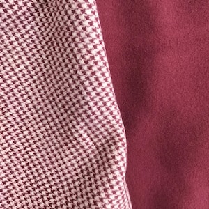 May include: Close-up of two fabric swatches. One is a burgundy and white houndstooth pattern, and the other is a solid burgundy color. The fabrics are likely for apparel or home decor.