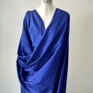 Peut inclure: Un tissu bleu roi drapé est présenté sur un mannequin. Le tissu est rassemblé et plié, créant un décolleté en V profond. Le matériau semble léger et fluide, avec des ombres et des reflets doux.