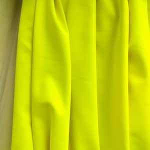 Peut inclure: Tissu jaune vif avec des plis souples. Le tissu a une texture lisse et une couleur unie vibrante. Les plis créent des ombres et des reflets, ajoutant de la profondeur à l'image. Le tissu semble être un matériau de poids moyen.