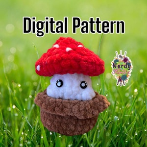 May include: A crocheted mushroom plush toy with a red cap, white stem, and brown base. The toy has googly eyes and is sitting on a bed of green grass.
