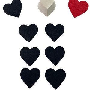 Puede incluir: Un conjunto de nueve corazones de fieltro en varios colores, incluyendo negro, blanco y rojo. Los corazones están dispuestos en un patrón, con el corazón blanco en la parte superior y los corazones negros en una fila debajo.