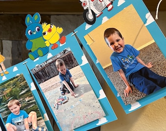 May include: A blue and white banner with clouds and photos of a young boy. The banner has a character from the movie Toy Story on it. The photos show the boy playing outside and smiling.