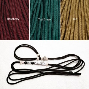 May include: Black paracord leash with a silver charm and white beads spelling "I LOVE MY PRINCE". The paracord is available in three colors: raspberry, teal green, and tan.