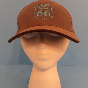 May include: A brown baseball cap with a blue embroidered Route 66 logo.