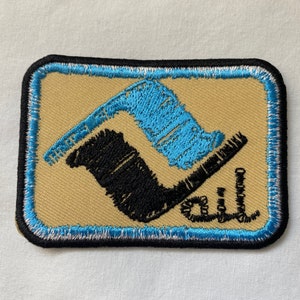 May include: A blue and black embroidered patch with a stylized design and the word "Gill" in cursive.