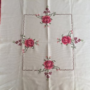 Puede incluir: Mantel blanco con un marco cuadrado bordado con cuatro rosas rosas y hojas verdes.