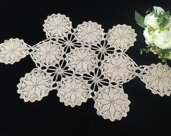 May include: A delicate, off-white crocheted doily with a floral pattern. The doily is made up of several connected flower shapes.