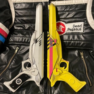 Two 3D printed ray gun props one painted like Party Poisons weapon from Danger Days music videos, one in white with black grips. Both laid side by side on top of a Party Poison cosplay jacket. Perfect for MCR fans, collectors & cosplay enthusiasts
